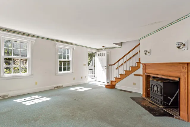 a view of an empty room with windows & fireplace