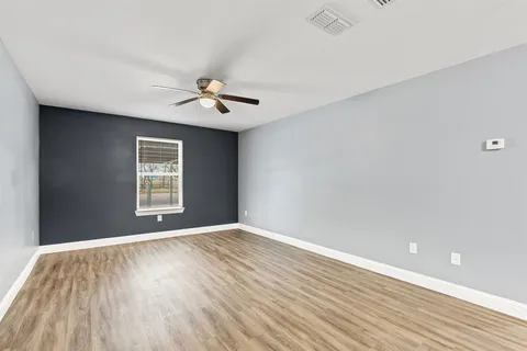 a view of an empty room with a window and wooden floor