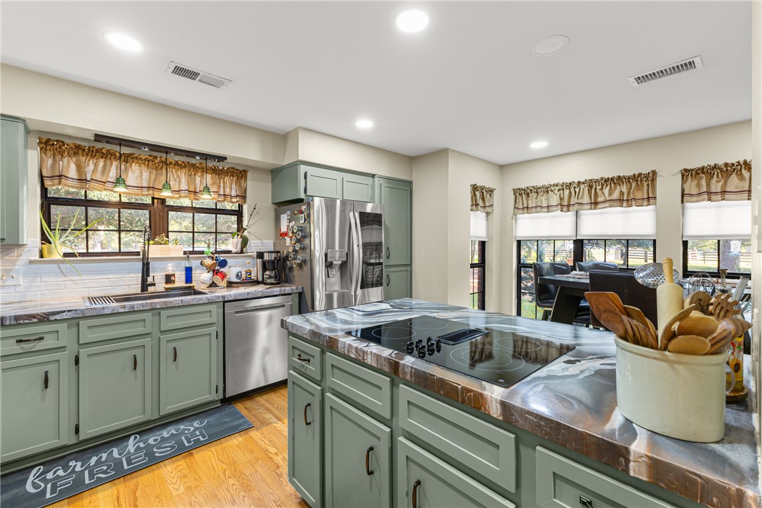 31928 Reids Prairie Road Waller, TX 77484 - Photo 11 of 43 Kitchen with green cabinetry, light wood-type flooring, stainless steel appliances, recessed lighting, and decorative backsplash
