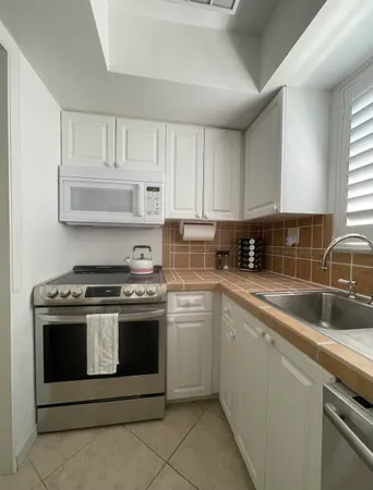 a kitchen with white cabinets appliances and a sink