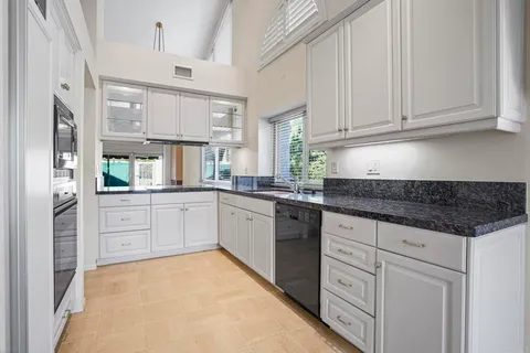 a kitchen with granite countertop white cabinets and white appliances