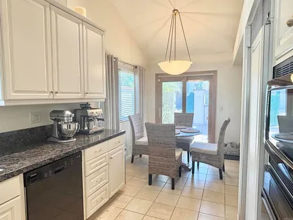 a kitchen with stainless steel appliances granite countertop a sink a stove a dining table and chairs with wooden floor