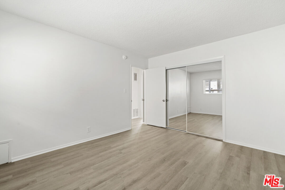 1236 McClellan Drive Los Angeles, CA 90025 - Photo 7 of 13 an empty room with wooden floor and mirror