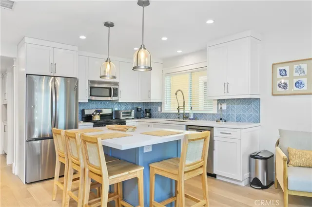 a large kitchen with kitchen island granite countertop a table chairs sink and refrigerator