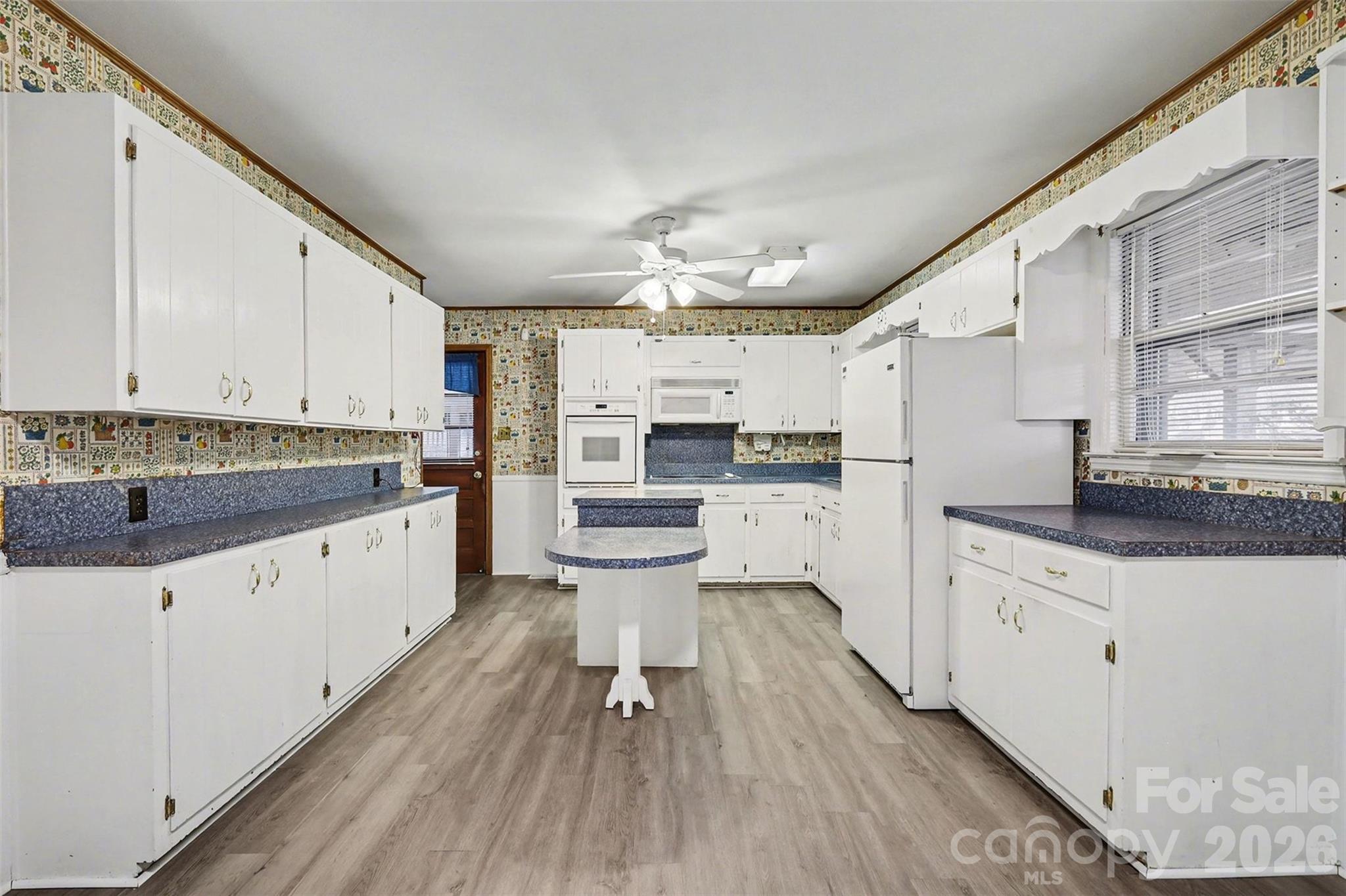 1343 Cedar Pines Lake Road Lancaster, SC 29720 - Photo 7 of 25 a large white kitchen with granite countertop a stove a sink dishwasher and white cabinets with wooden floor