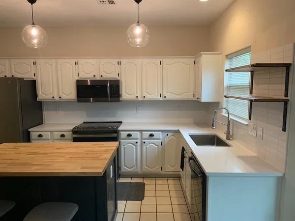 a kitchen with stainless steel appliances granite countertop a sink a stove a refrigerator a center island a stove and a cabinets