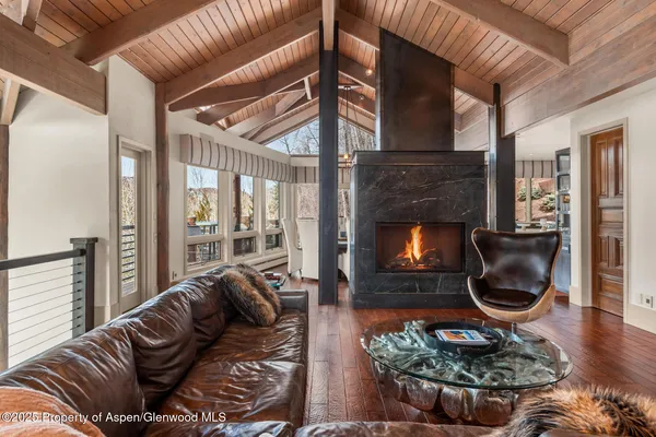 a living room with furniture a fireplace and a floor to ceiling window