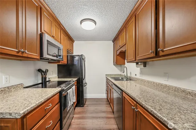 a kitchen with stainless steel appliances granite countertop a sink a stove and a wooden cabinets
