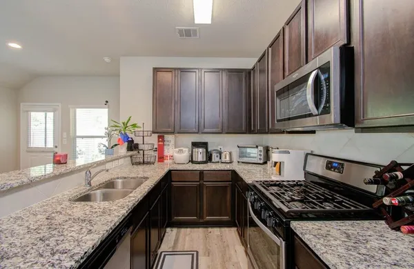 a kitchen with stainless steel appliances granite countertop a sink stove and cabinets