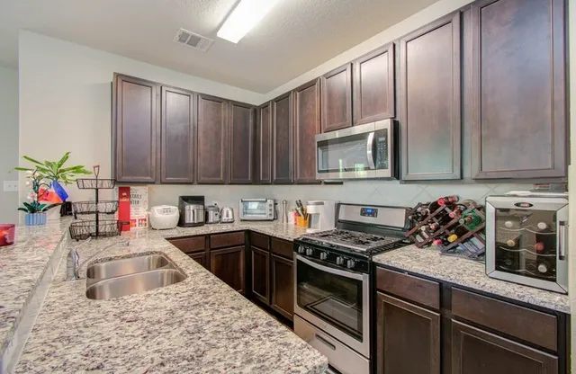 a kitchen with kitchen island granite countertop a sink dishwasher stove and cabinets with wooden floor