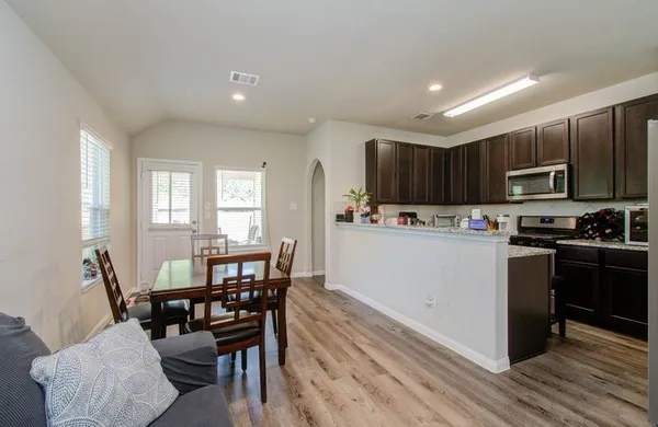 a kitchen with kitchen island granite countertop wooden floors wooden cabinets dining table and chairs
