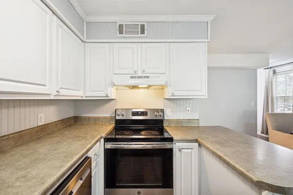 a kitchen with granite countertop white cabinets and stainless steel appliances