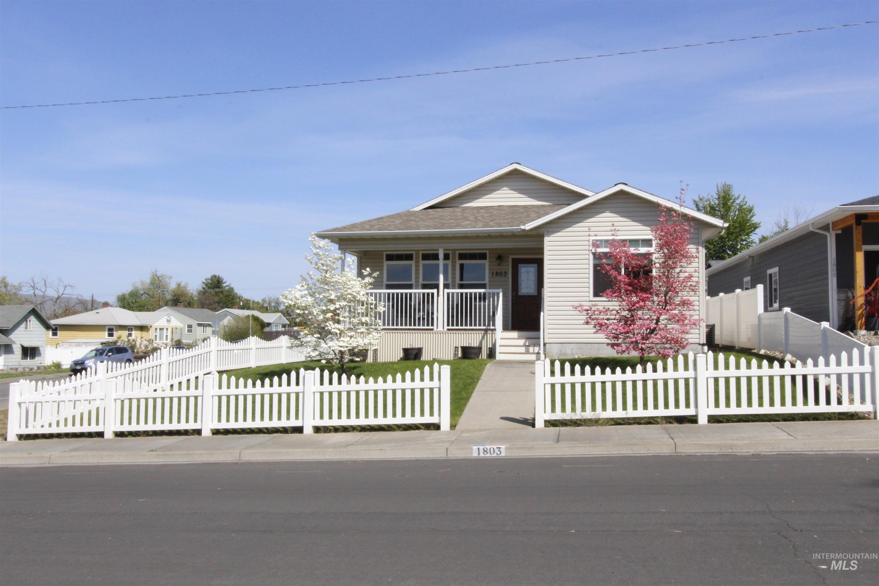 Single-story residence featuring light-colored siding and a white picket fence