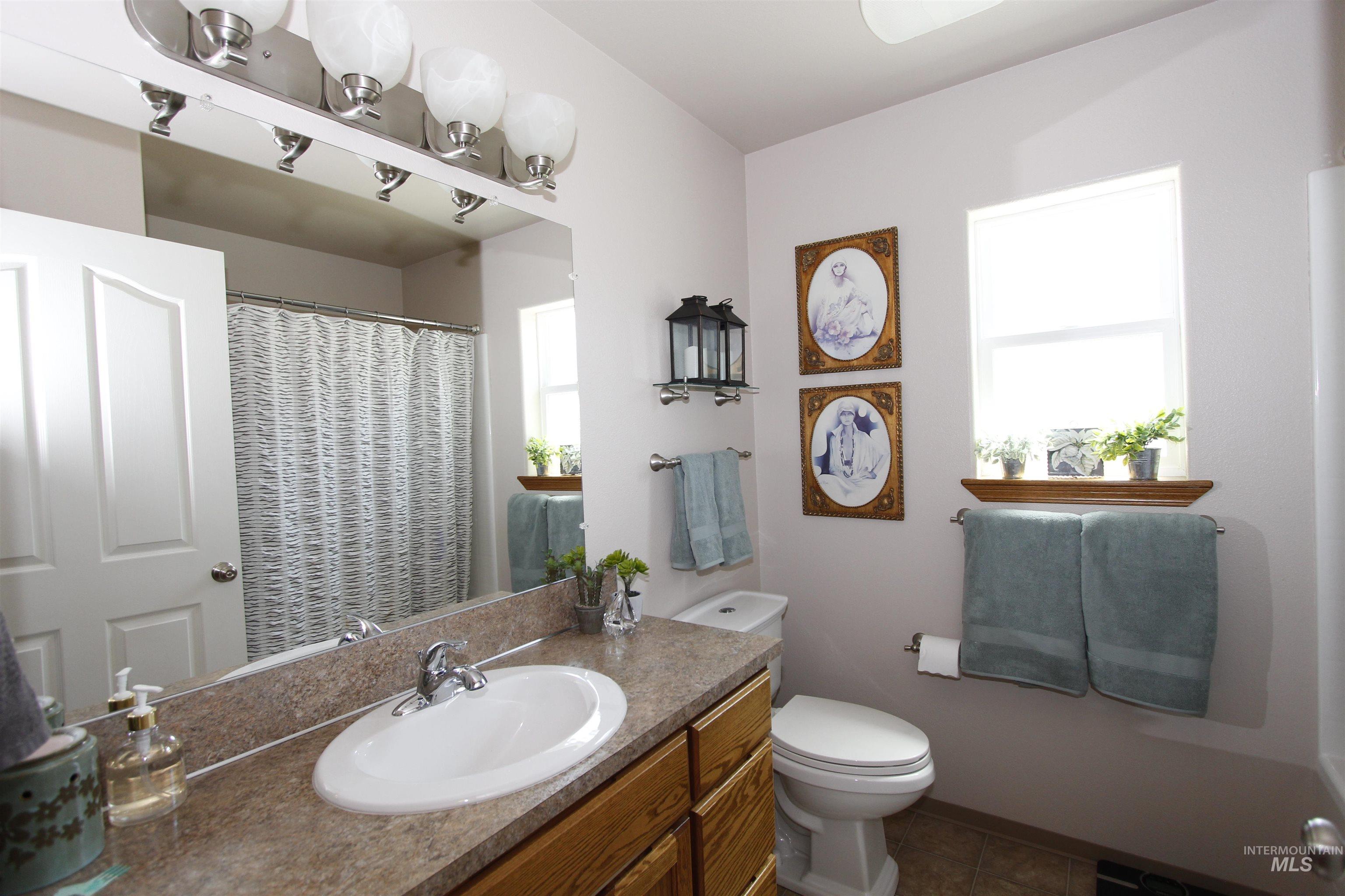 1803 16th Street Lewiston, ID 83501 - Photo 18 of 22 Bathroom featuring a light wood-finish vanity with a single basin sink, laminate countertop, and a large wall mirror