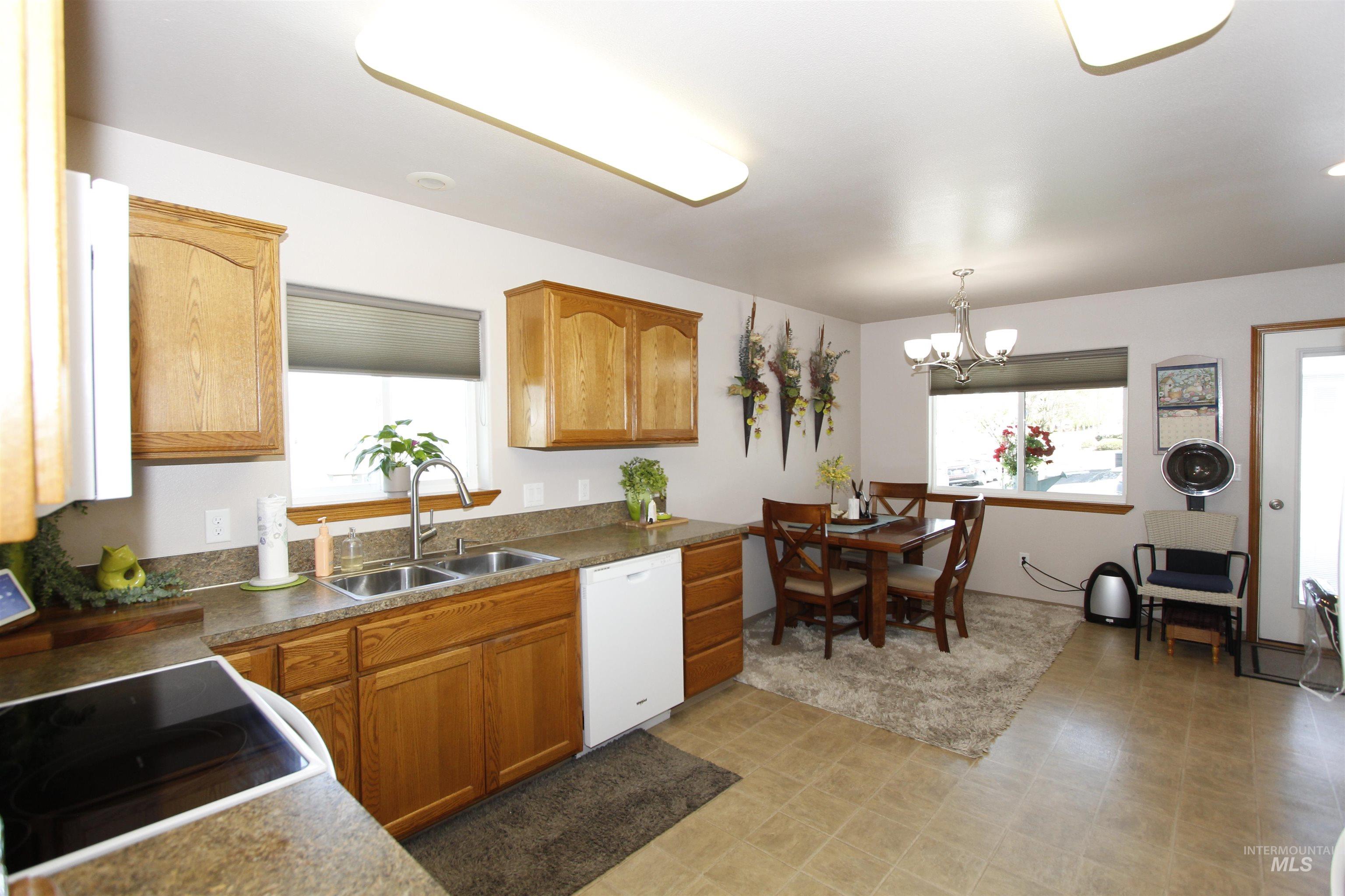 1803 16th Street Lewiston, ID 83501 - Photo 6 of 22 Kitchen featuring wood cabinetry, laminate countertops, a double basin stainless steel sink, and a white dishwasher