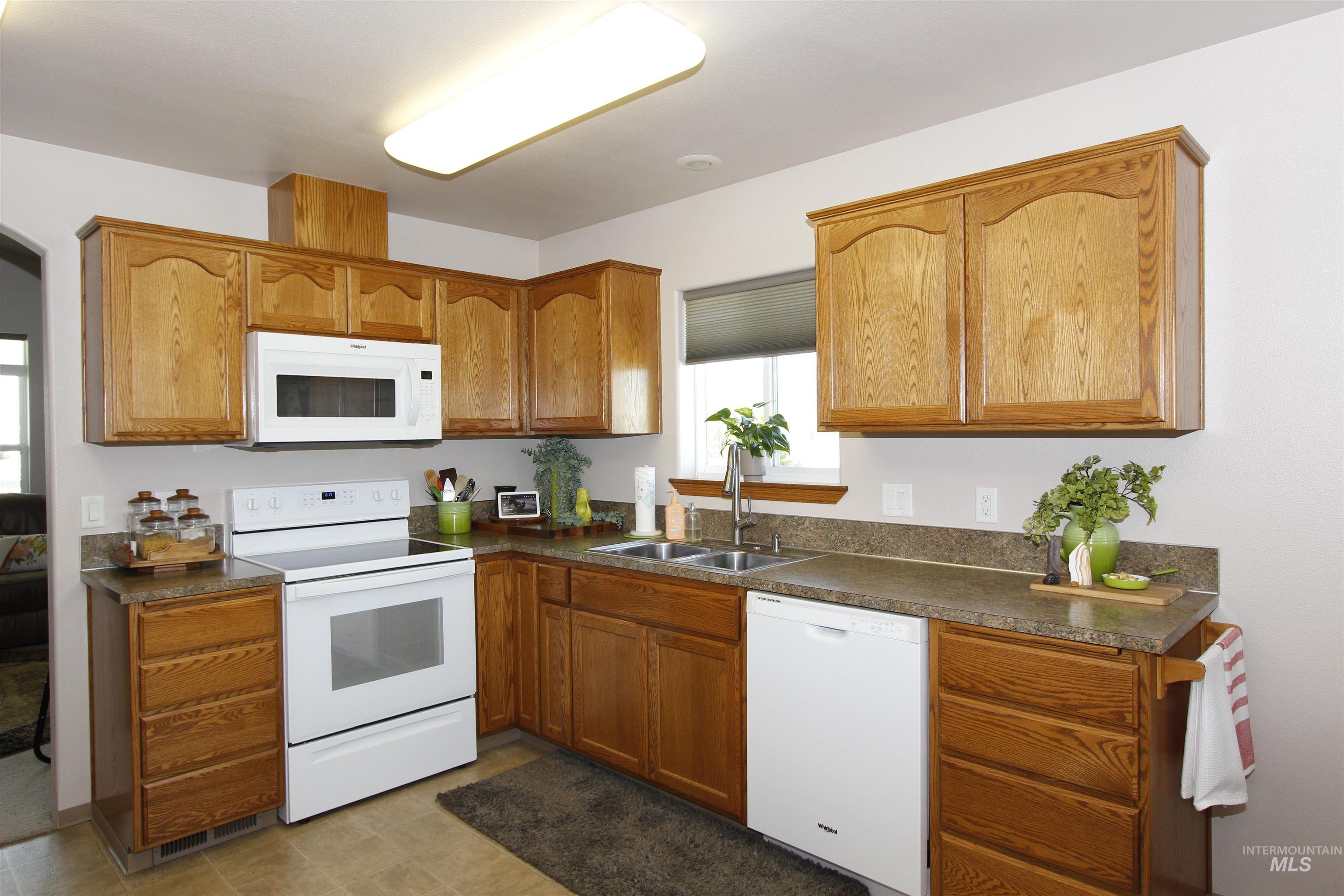 1803 16th Street Lewiston, ID 83501 - Photo 7 of 22 Kitchen featuring oak cabinetry, granite-style countertops, white appliances, stainless steel sink, and tile flooring