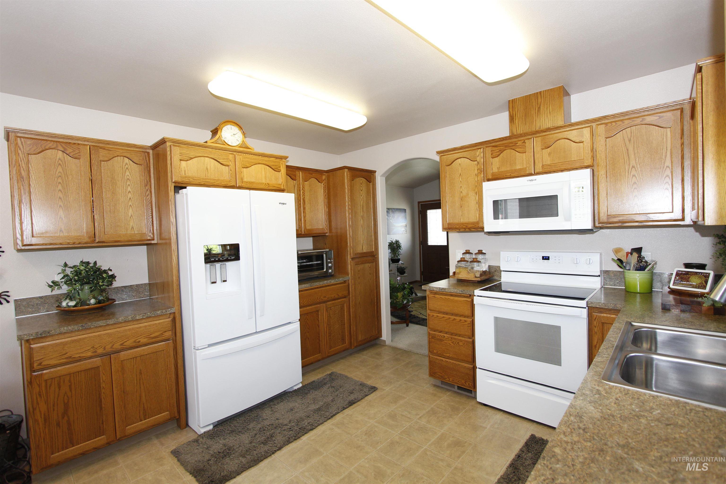 1803 16th Street Lewiston, ID 83501 - Photo 8 of 22 Kitchen featuring oak cabinetry, white appliances including a side-by-side refrigerator, built-in microwave, and electric range, laminate countertops, and tile flooring