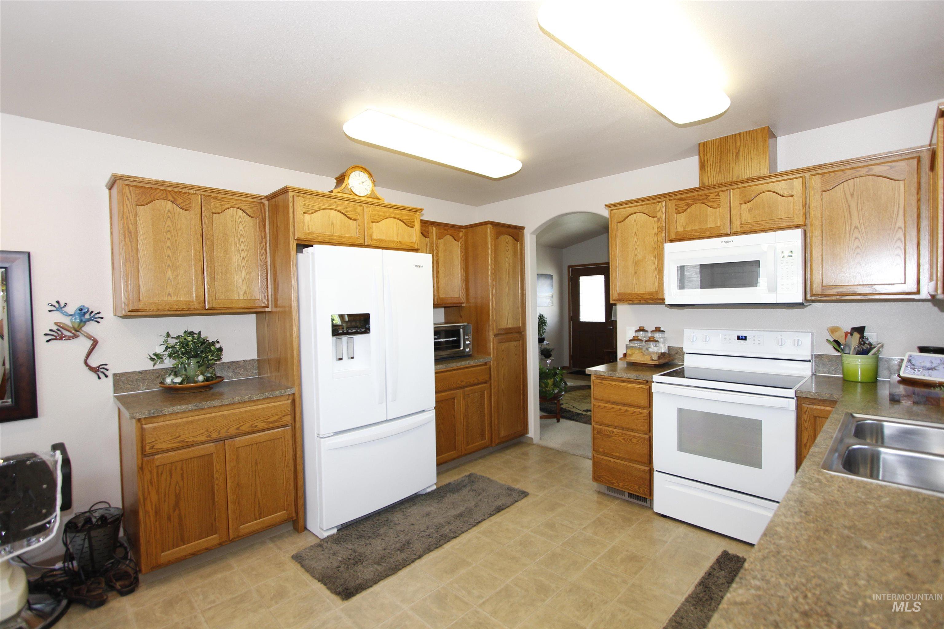 1803 16th Street Lewiston, ID 83501 - Photo 9 of 22 Kitchen featuring wood-finish cabinetry, white appliances, and laminate countertops