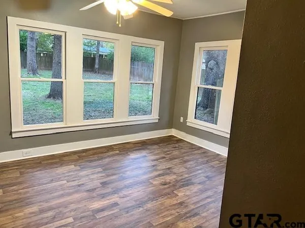 a view of an empty room with wooden floor and a window