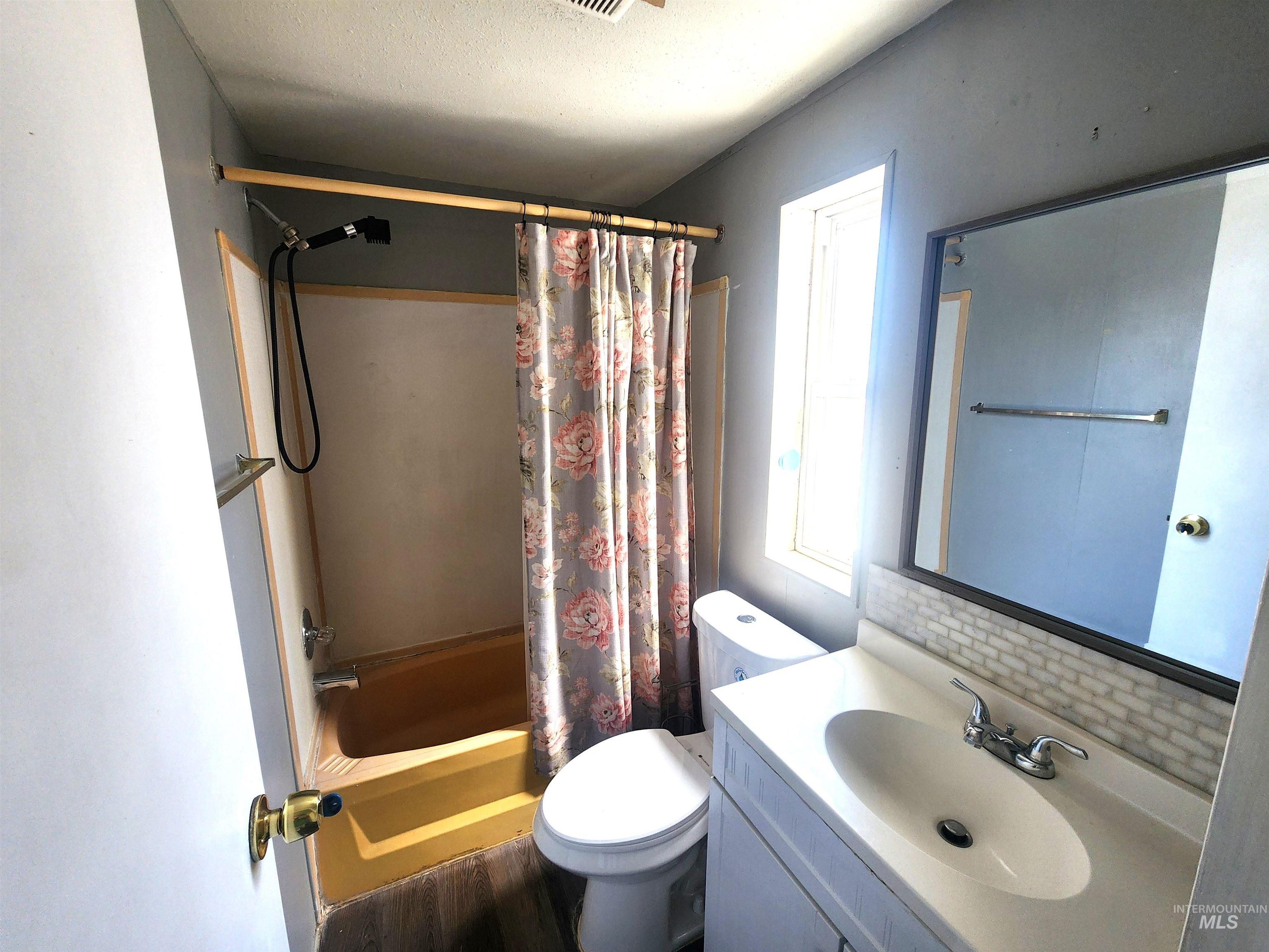 616 North Kings Road Nampa, ID 83687 - Photo 10 of 12 Bathroom featuring a single vanity with an integrated sink, a rectangular mirror, and a window
