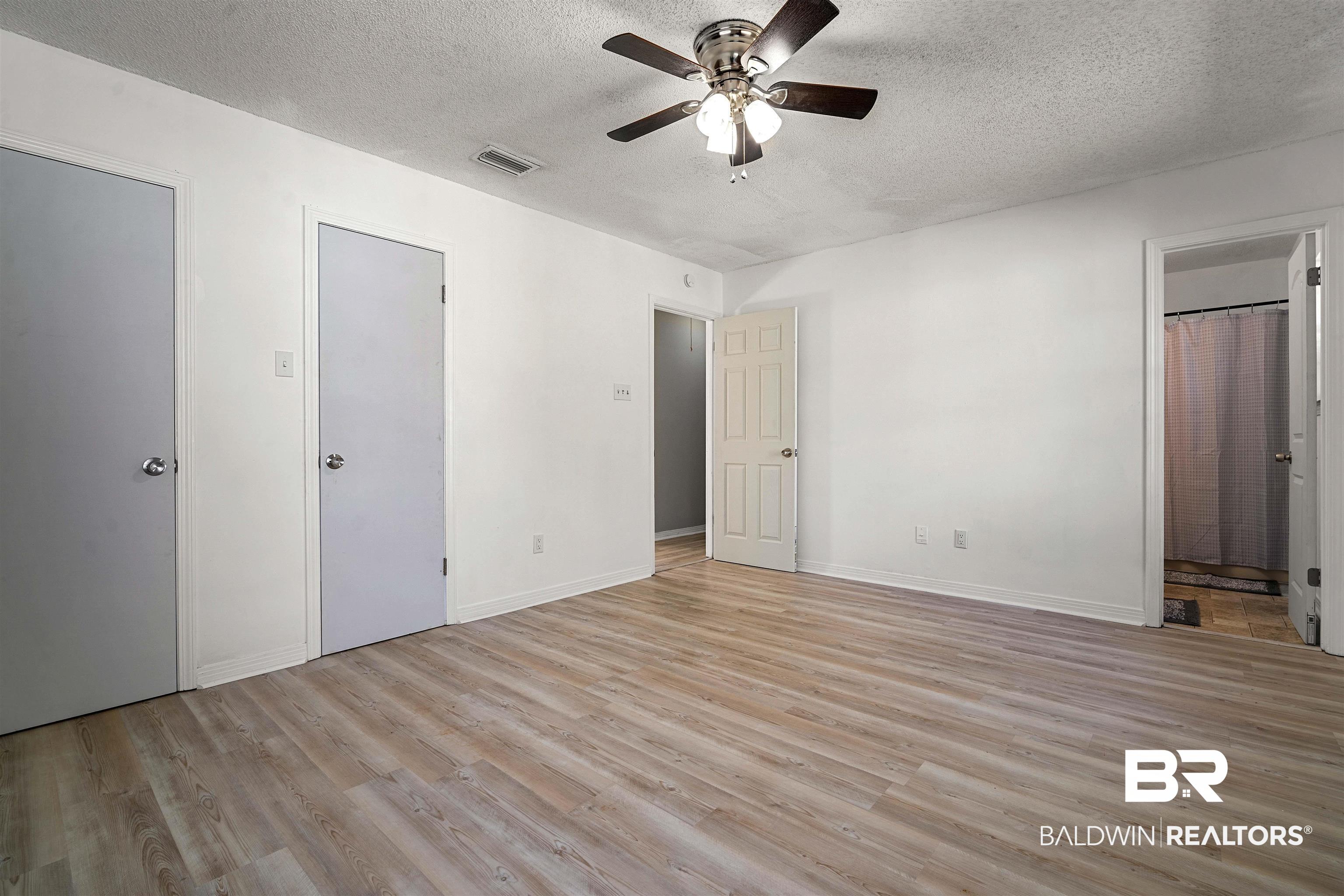 12910 Del Rio Street Grand Bay, AL 36541 - Photo 15 of 26 Unfurnished bedroom with light wood-style flooring, a textured ceiling, a ceiling fan, and ensuite bathroom