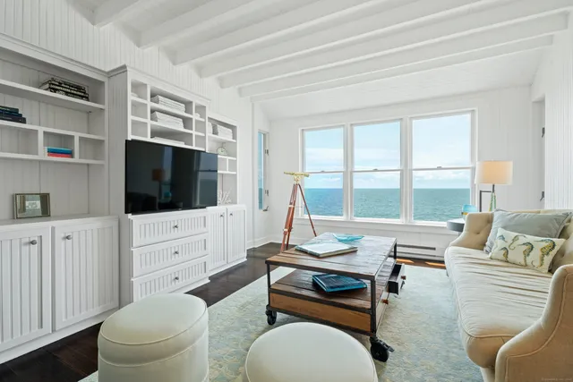 a living room with furniture a flat screen tv and a floor to ceiling window