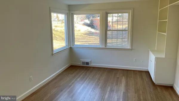 an empty room with wooden floor and windows