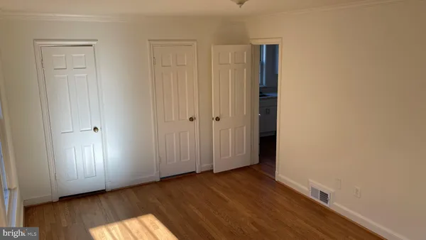 an empty room with wooden floor and closet area