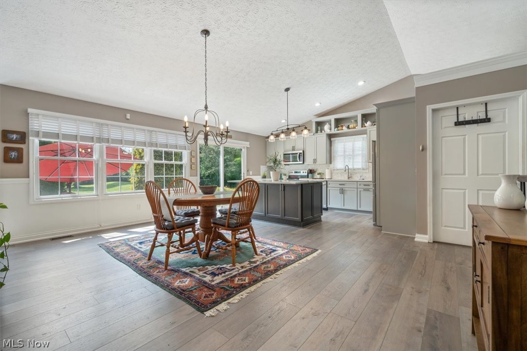 24876 Quarry Road Wellington, OH 44090 - Photo 13 of 50 Dining room with vaulted ceiling, a textured ceiling, light wood-type flooring, and a chandelier