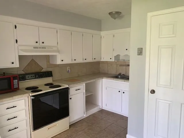 a kitchen with granite countertop white cabinets and stainless steel appliances