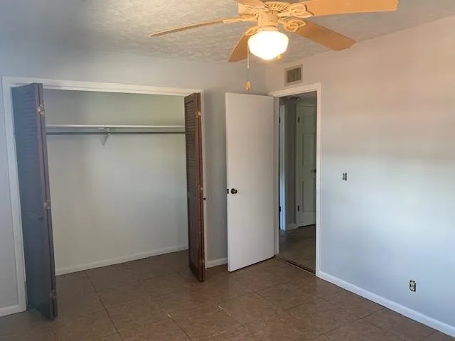 a view of an empty room with a chandelier fan