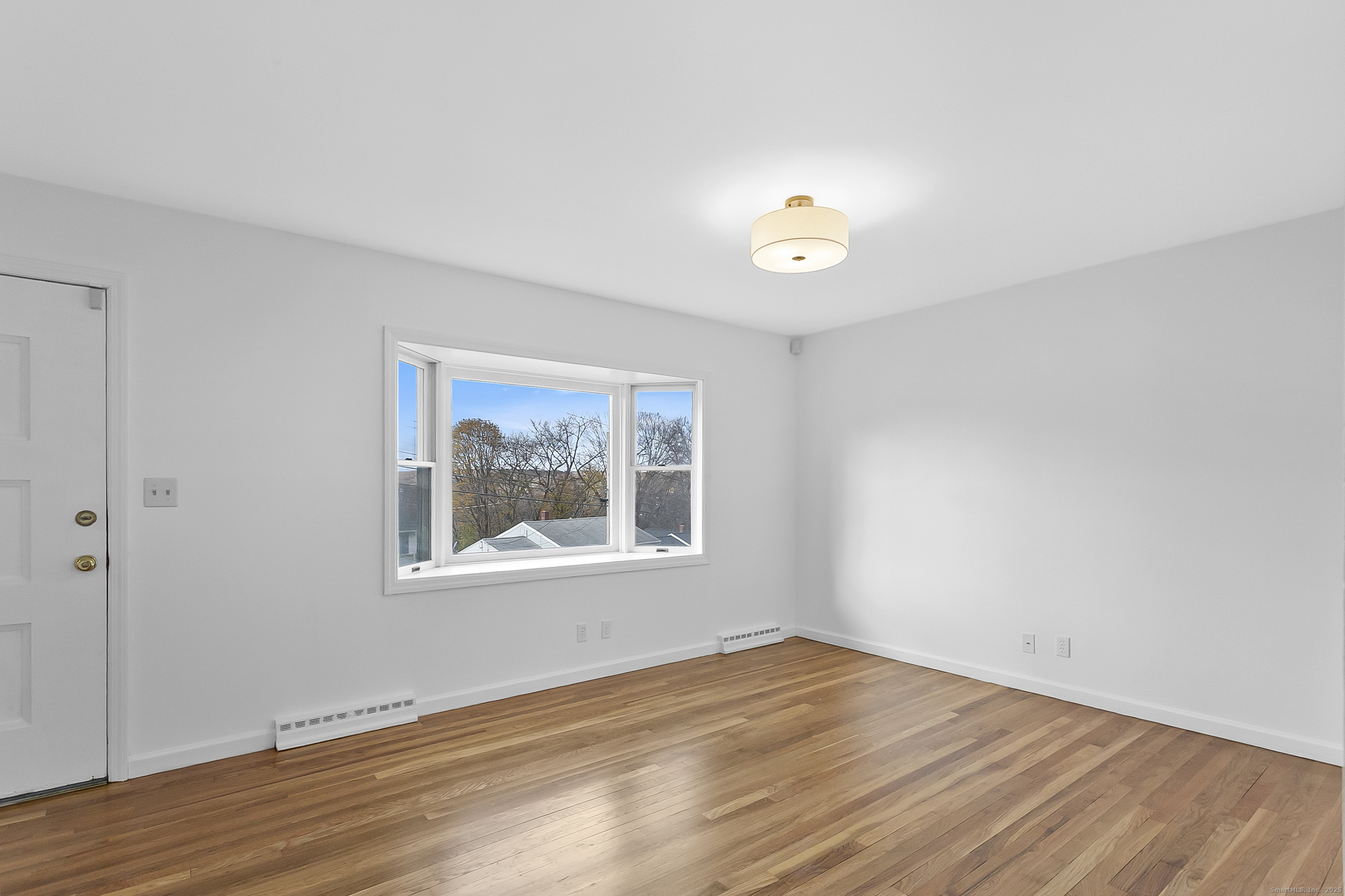 23 Berkshire Road Ansonia, CT 06401 - Photo 5 of 23 an empty room with wooden floor and windows