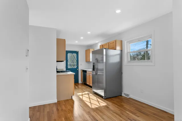 a view of a kitchen with refrigerator and wooden floor