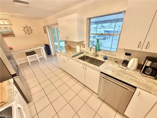 a white kitchen with a sink a stove and a window