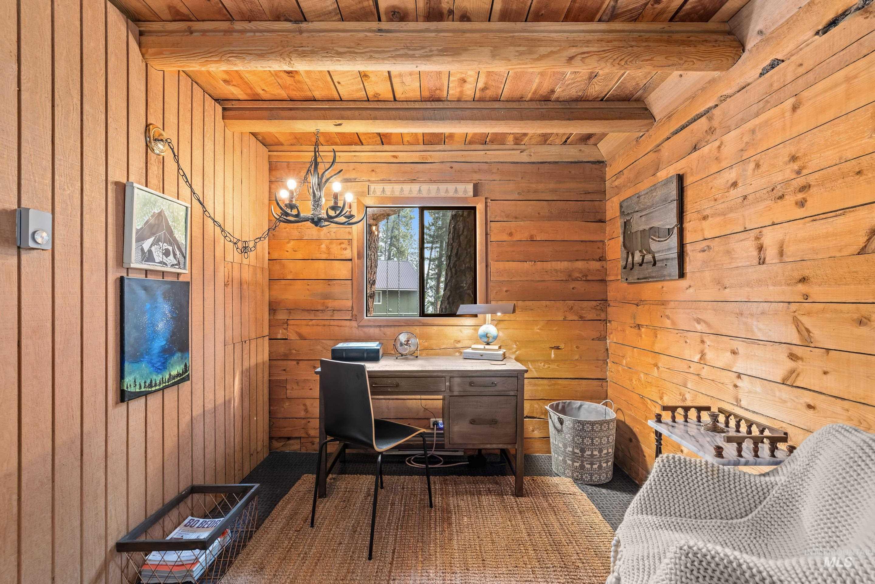 73 Rainbow Ridge Road Garden Valley, ID 83622 - Photo 38 of 49 Wood-paneled walls, exposed wood beam ceiling, window with exterior landscape, and a wrought iron style chandelier