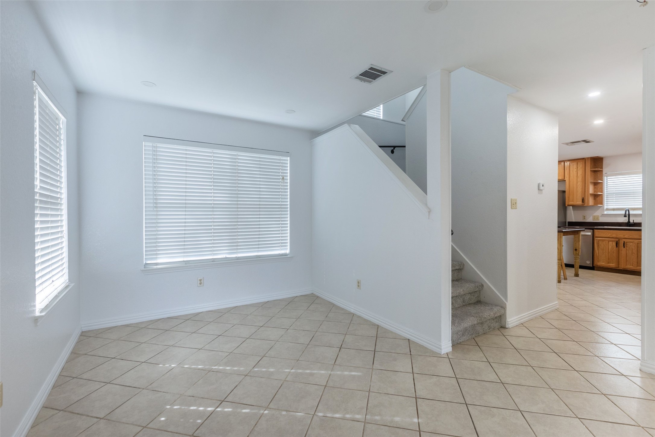 8506 Bisbee Court Austin, TX 78745 - Photo 4 of 20 Open-concept living area featuring tile flooring, multiple windows with blinds, a carpeted staircase, and recessed lighting