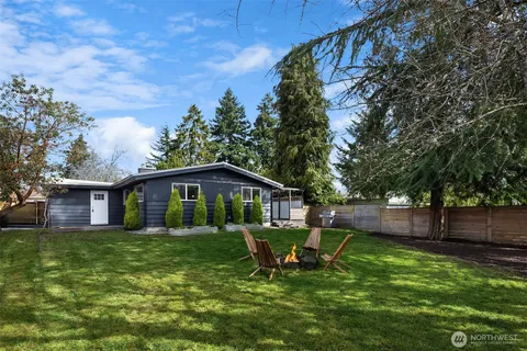 a view of a wooden house with a yard and large trees