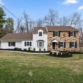 a front view of a house with a garden and trees