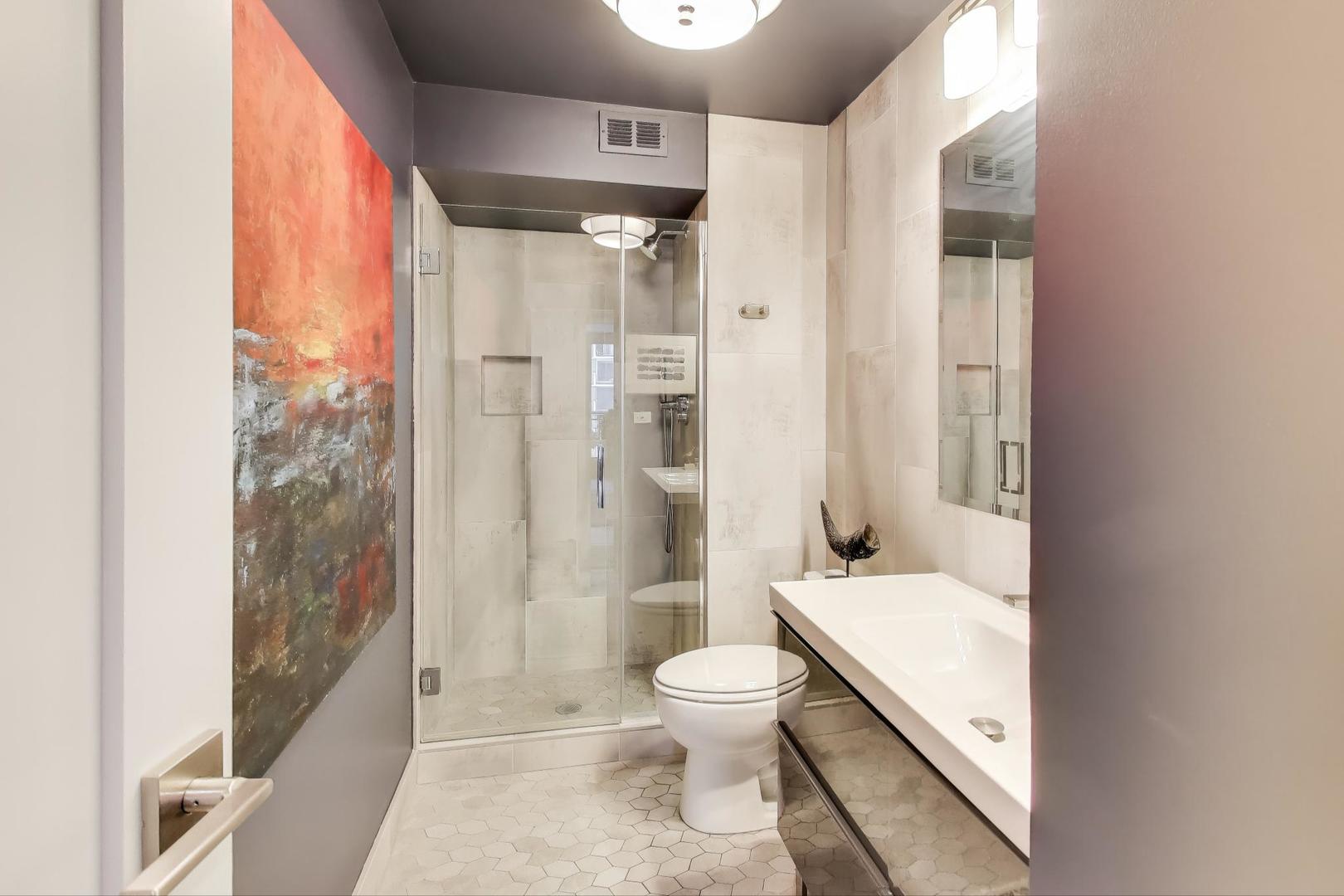 6007 North Sheridan Road, Unit 12B Chicago, IL 60660 - Photo 23 of 38 a bathroom with a toilet a sink and a large mirror