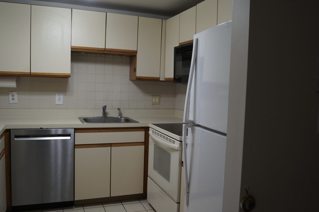 200 Ledgewood Drive, Unit 205 Stoneham, MA 02180 - Photo 5 of 18 a kitchen with stainless steel appliances granite countertop a refrigerator and a sink