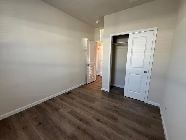 an empty room with wooden floor and closet