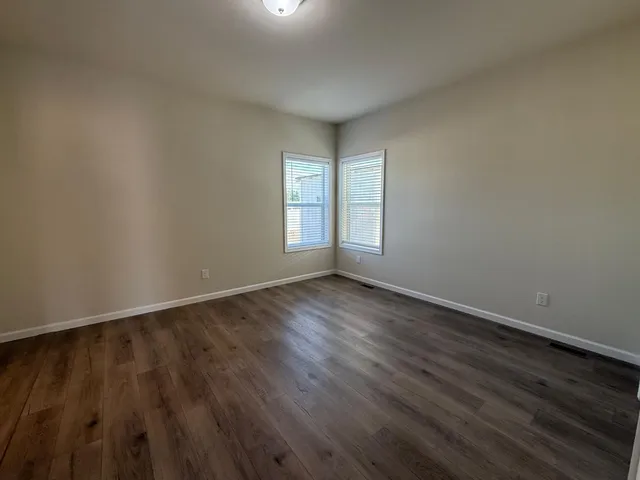 a view of an empty room with wooden floor and window