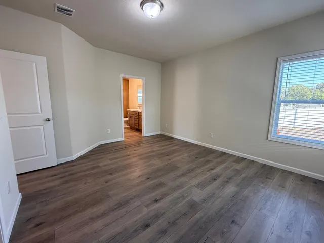 an empty room with wooden floor and windows