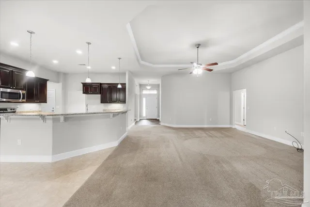 a view of an empty room and kitchen with fireplace