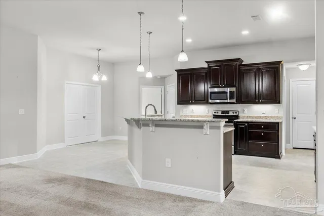 a kitchen with stainless steel appliances granite countertop a refrigerator a sink a stove a microwave and wooden floor