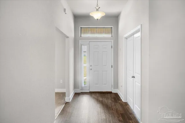 an empty room with wooden floor closet and windows