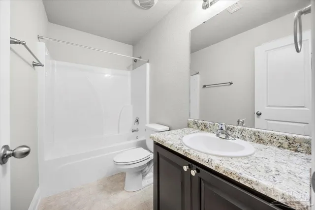a bathroom with a granite countertop sink a toilet and shower