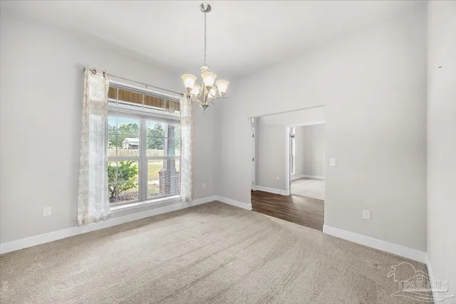 a view of an empty room with chandelier and window