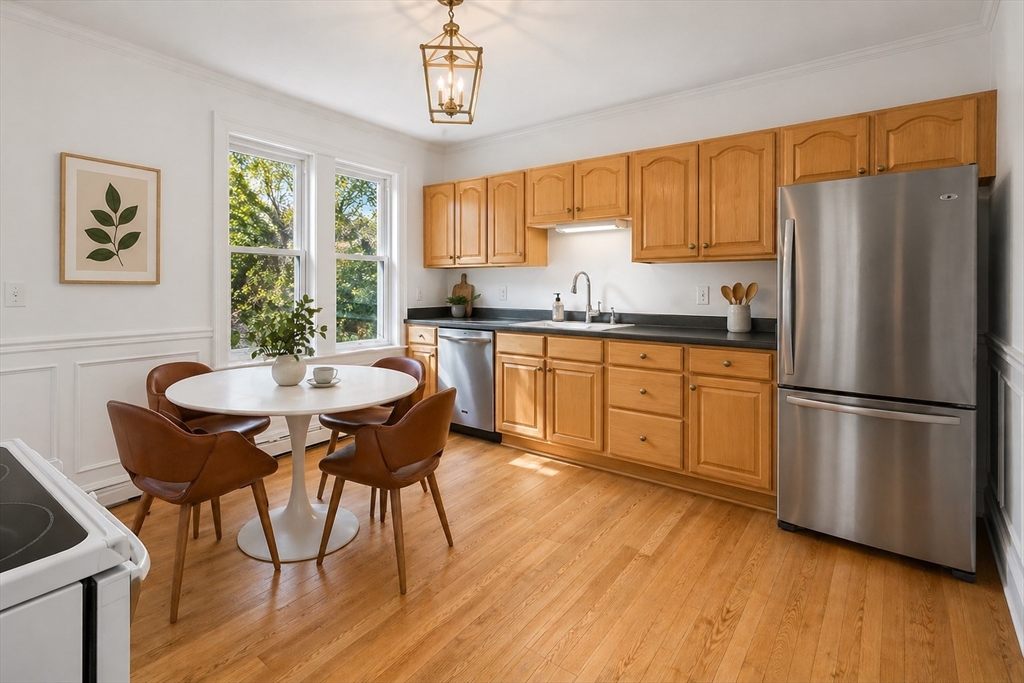 215 Ash Street, Unit 3 Waltham, MA 02453 - Photo 13 of 18 a kitchen with stainless steel appliances granite countertop a refrigerator a stove a sink a dining table and chairs with wooden floor