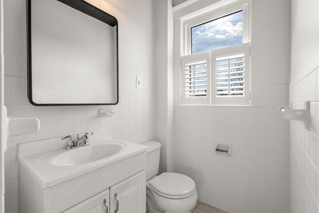 215 Ash Street, Unit 3 Waltham, MA 02453 - Photo 5 of 18 a bathroom with a toilet a sink a mirror and a window
